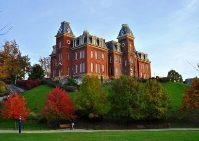 Woodburn Building at WVU on the hill in the fall, surrounded by trees and blue sky